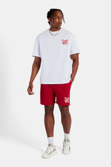 Weißes Oversize-T-Shirt mit gesticktem Wappen und rote Jersey-Shorts