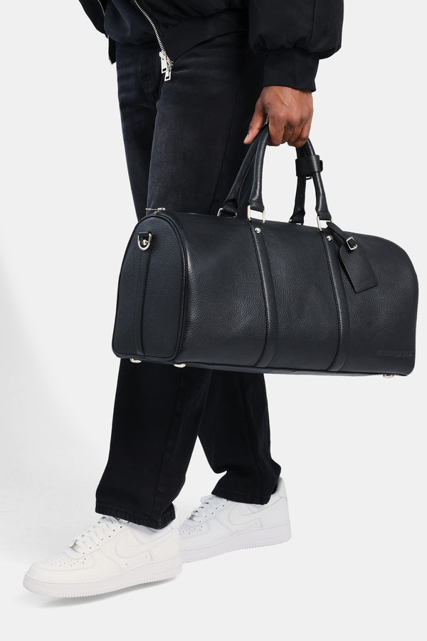 Male model holding the black leather duffle bag 