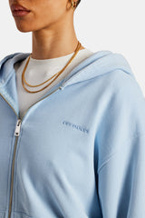 Femal model close up of the cernucci zip through hoodie in light blue and the small cernucci logo 