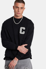 Male Model wearing black sweater with embellished C detail 