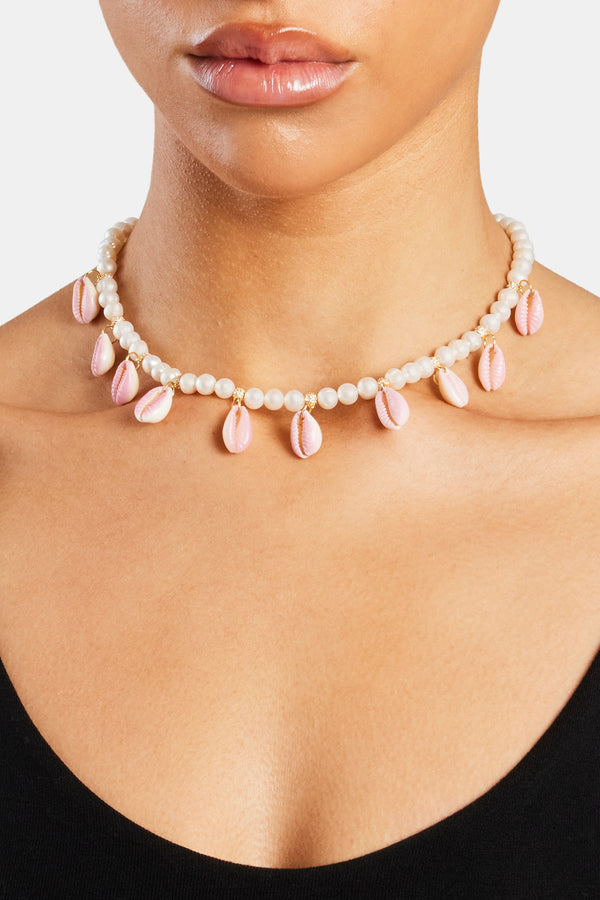 Female model wearing the Freshwater Pearl Pink Cowrie Shell Necklace in gold with white background